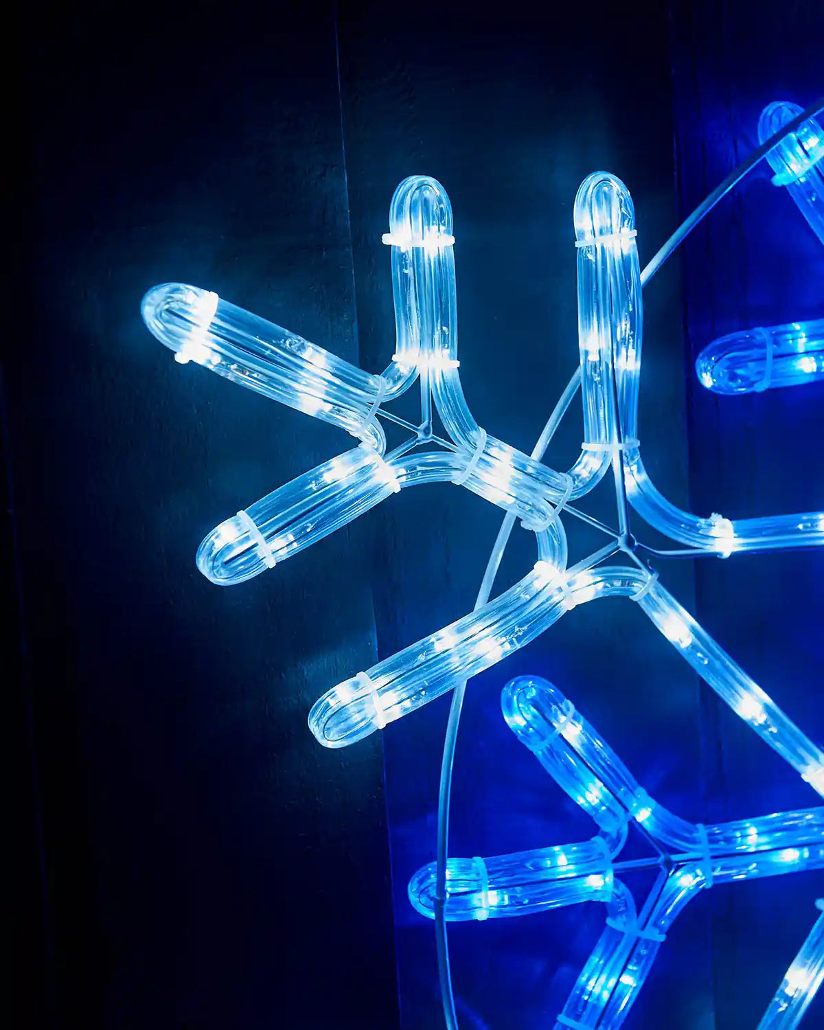 Close up of the edge of a blue and white  LED snowflake on a fence  
