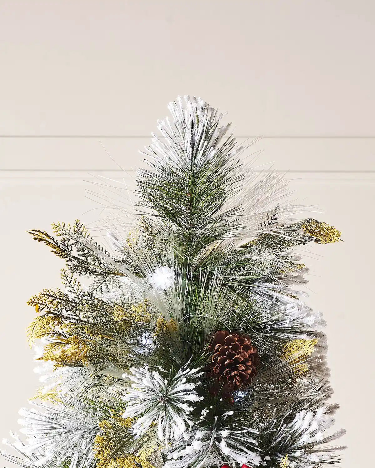 Close up of top of Christmas tree with snow flock, pinecones and white lights