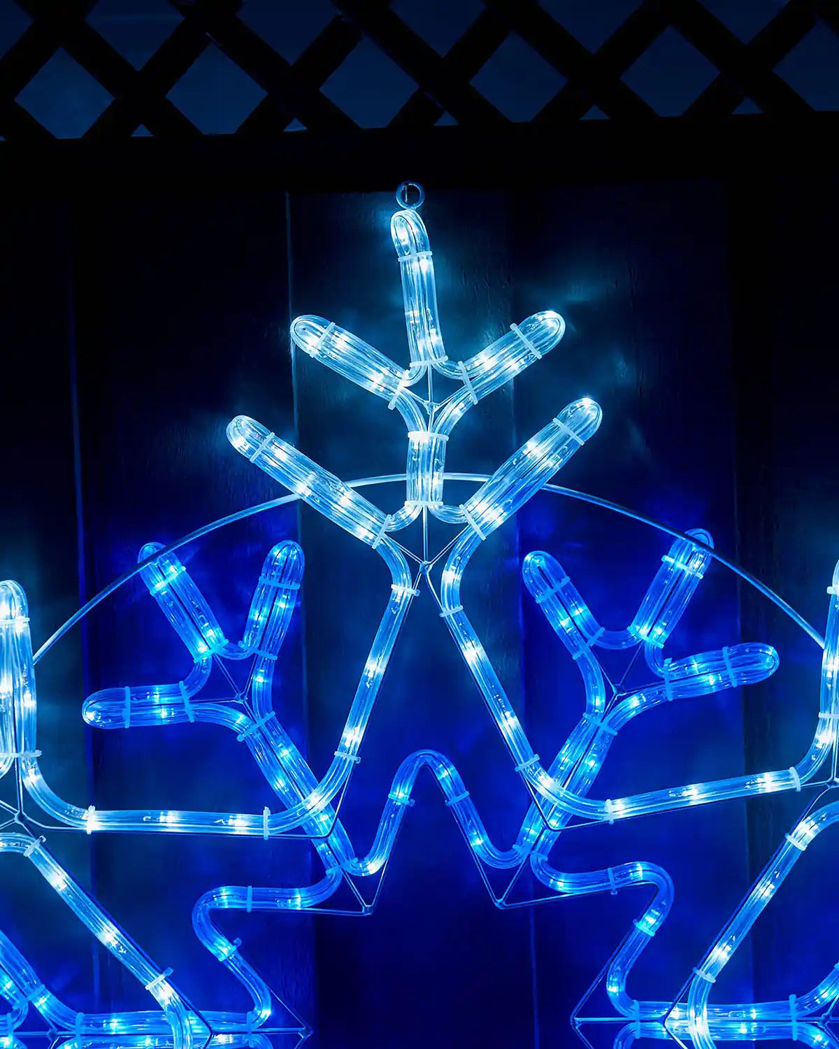 Close up of top of blue and white LED snowflake on a fence  