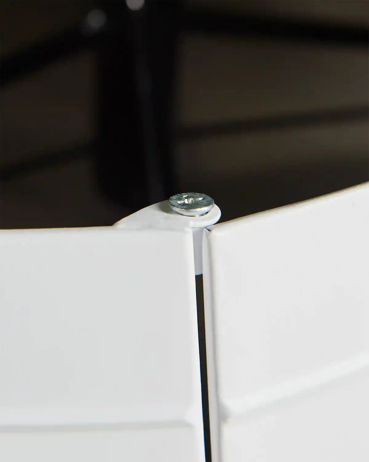 Close-up of white metal tree skirt hinge with screw holding hinge in place 