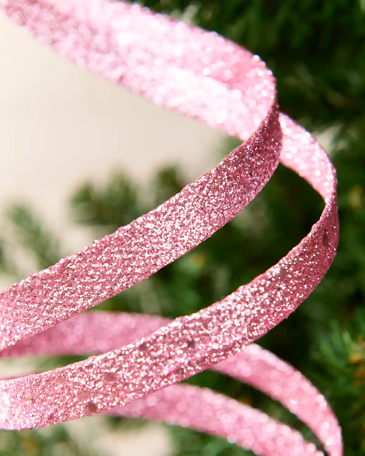 Close up pink Glitter Spiral Swirl Pick showing pink glitter details with green and cream blurred background