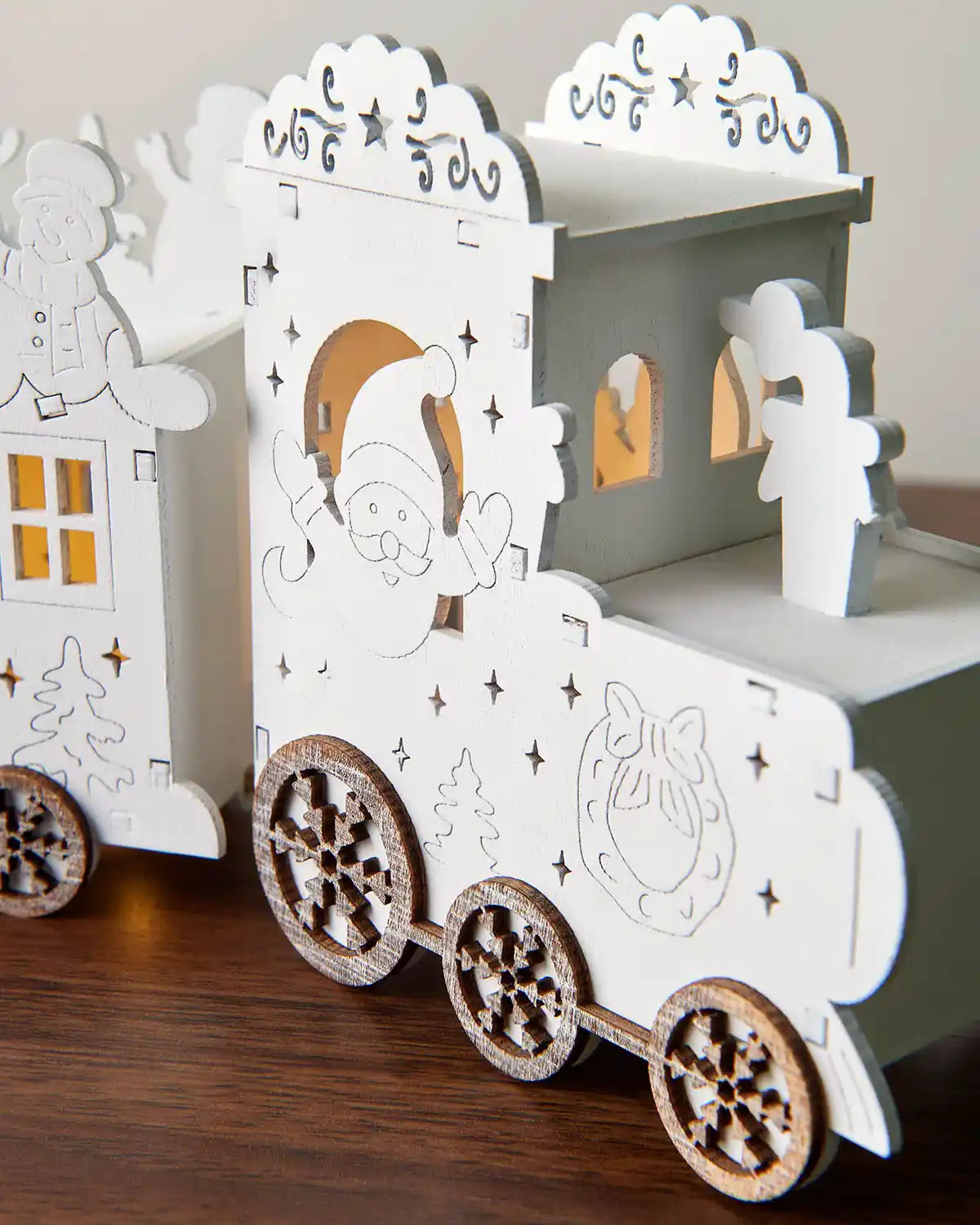 Close-up of front of pre-lit white wooden train with warm white light on dark wood surface