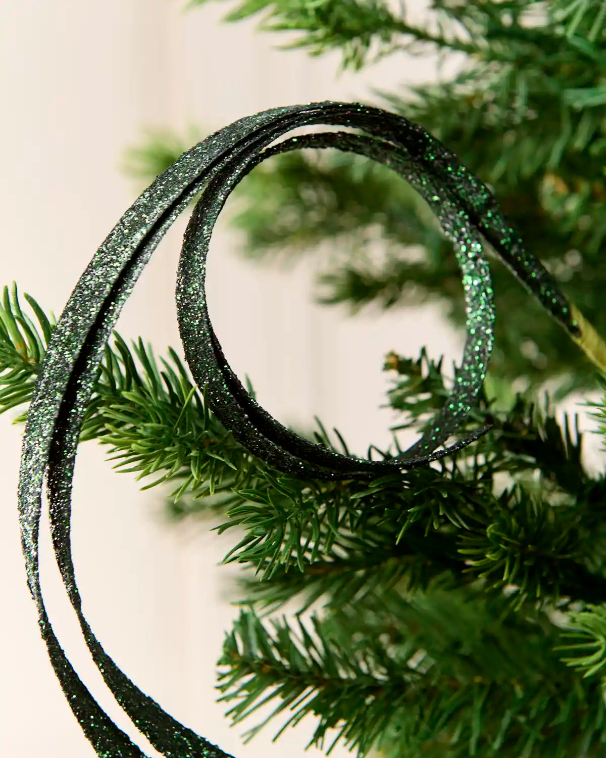 Close up sage green Glitter Spiral Swirl Pick with green and cream blurred background