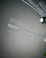 Close-up of foliage part of silver glitter bauble spray in front of grey background