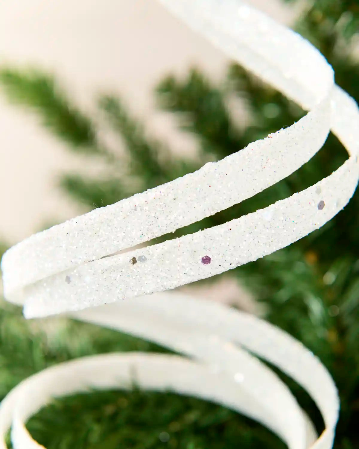 Close up white Glitter Spiral Swirl Pick showing white glitter details with green and cream blurred background