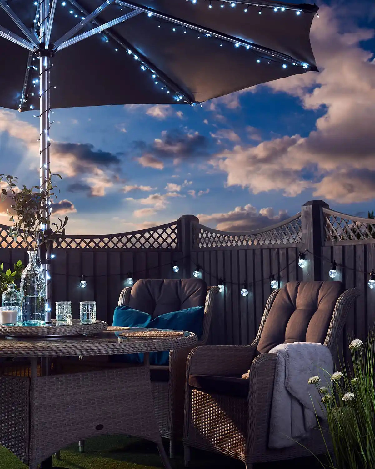 Cloudy sky with garden furniture, ice white fairy lights on an umbrella pole  