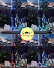 Colour-changing LED string lights on a decorative stand with candles and glasses against a cloudy blue sky