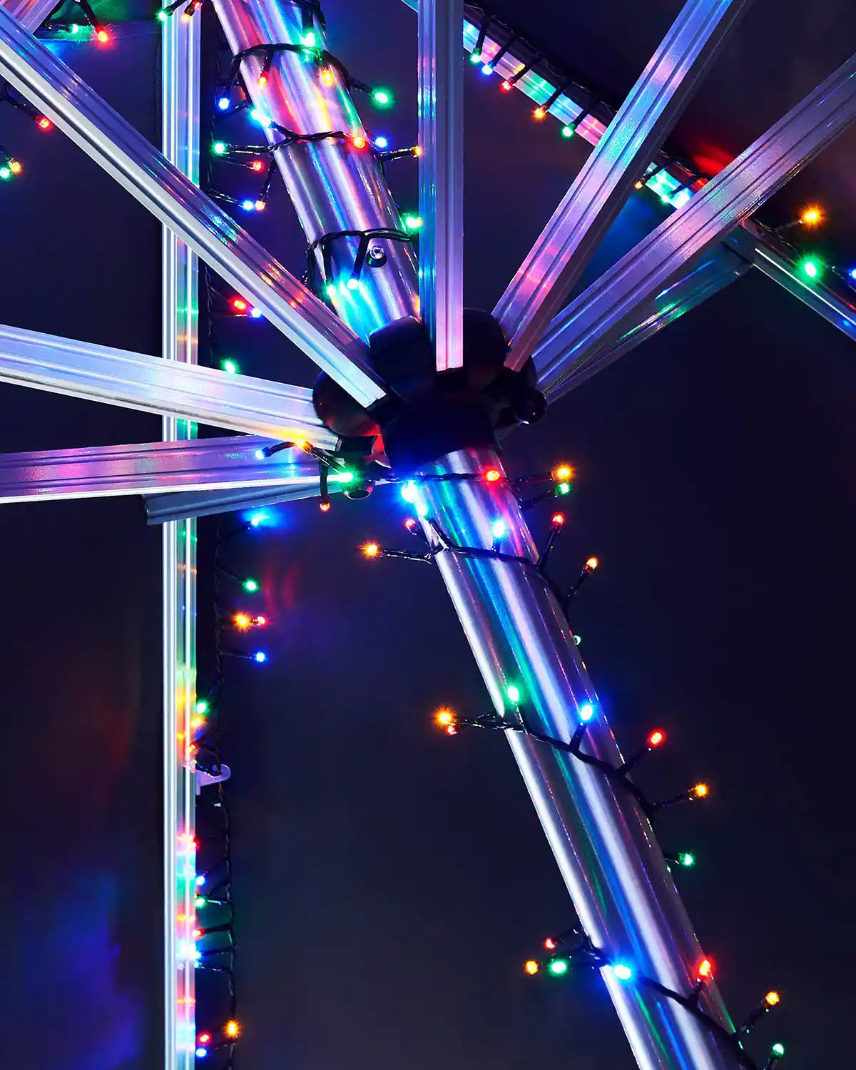 Colourful LED lights on a umbrella post against a dark background