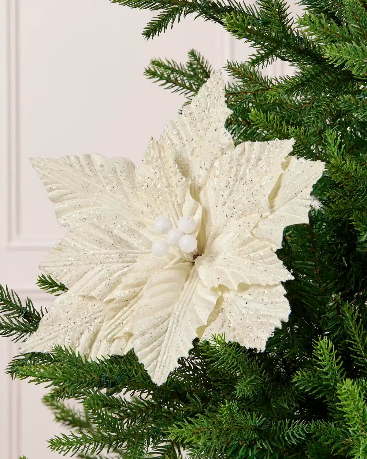 Cream glitter artificial poinsettia displayed on a Christmas tree