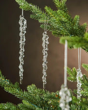 Crystal icicle ornaments hanging on a Christmas tree branch with a brown background