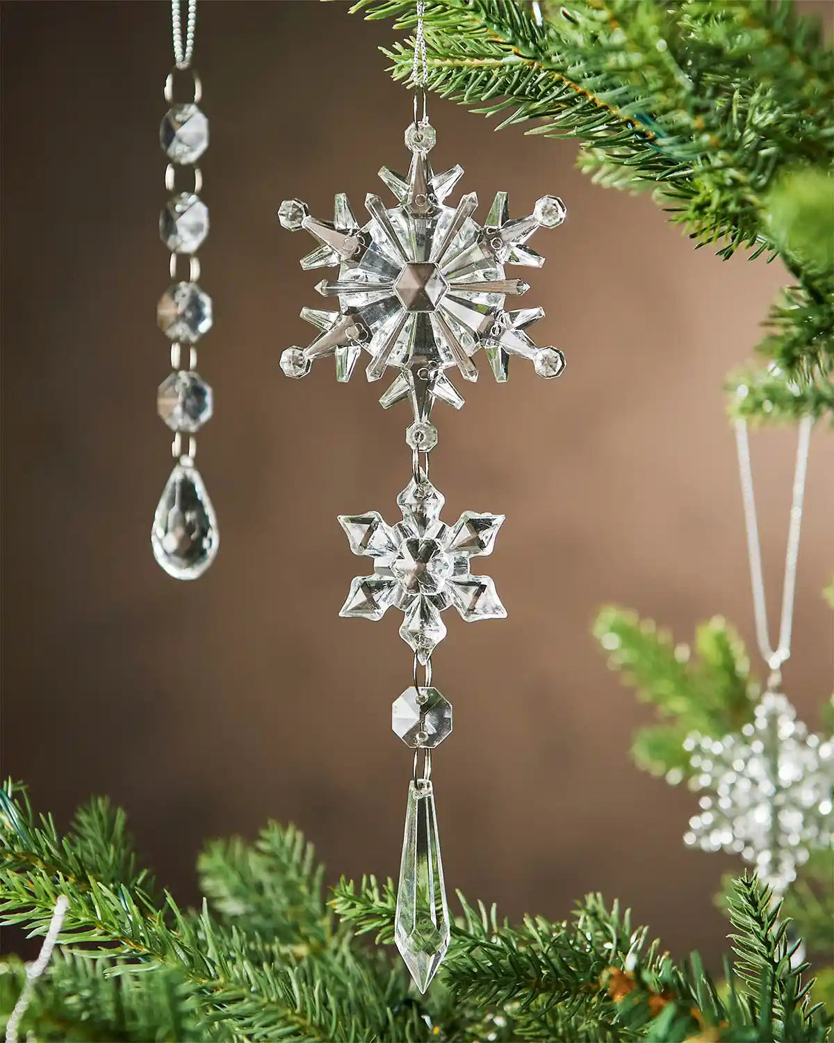 Crystal snowflake ornament hanging on a Christmas tree with a brown background