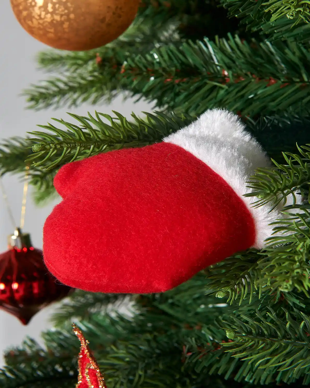 Close up of Snowman Red glove with White fluffy trim on a Christmas tree with red and gold baubles