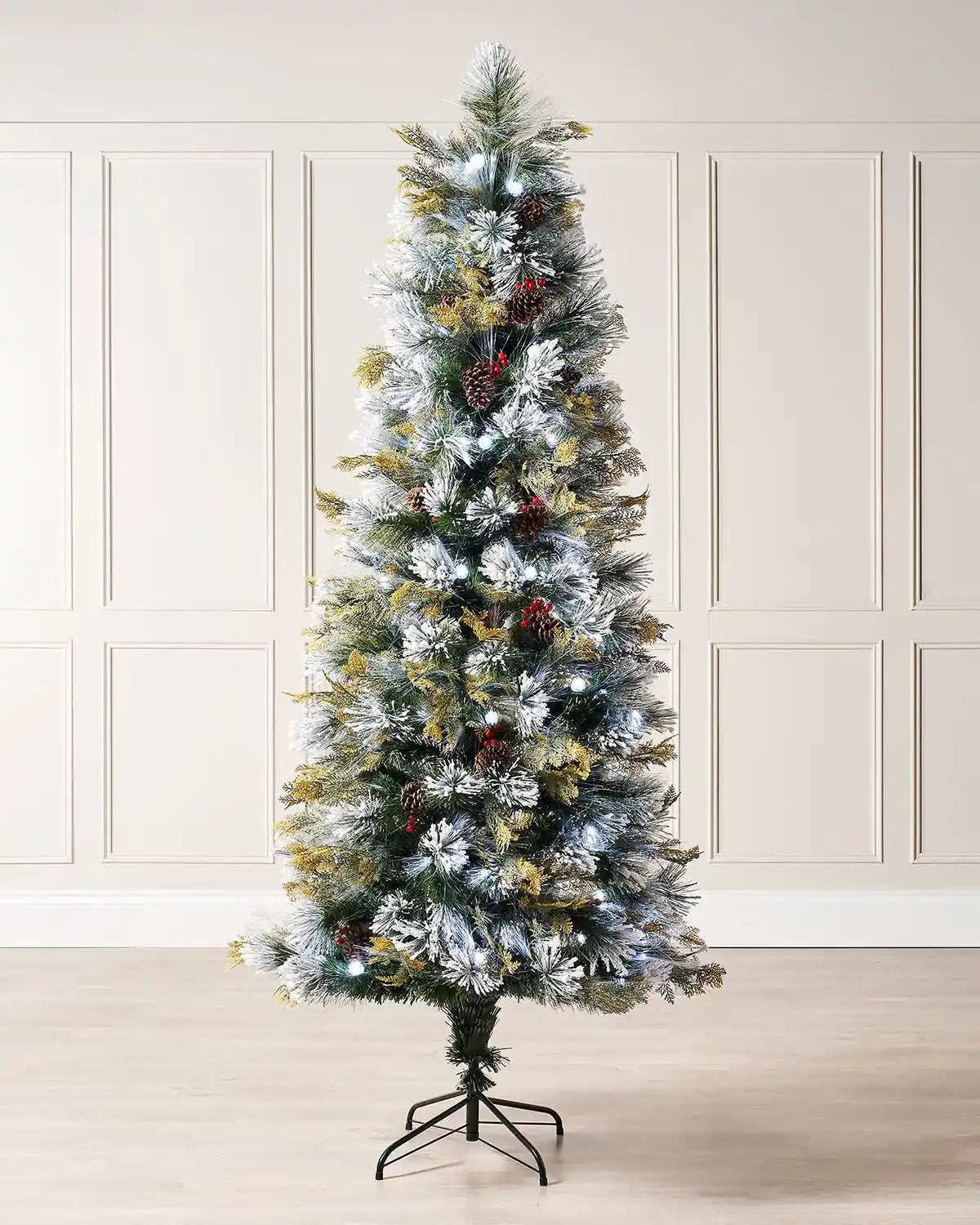 Decorated Christmas tree with Red berries, pinecones and white lights on a cream panel wall