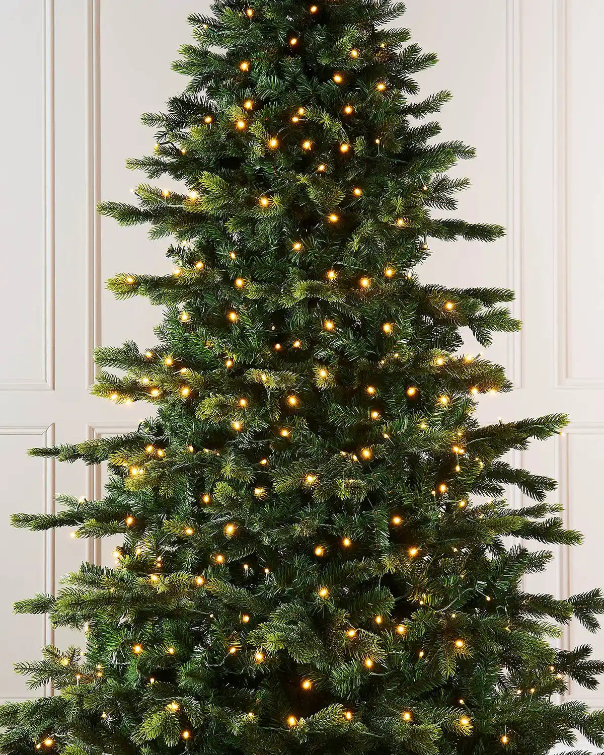 Decorated Christmas tree with lights against a white wall