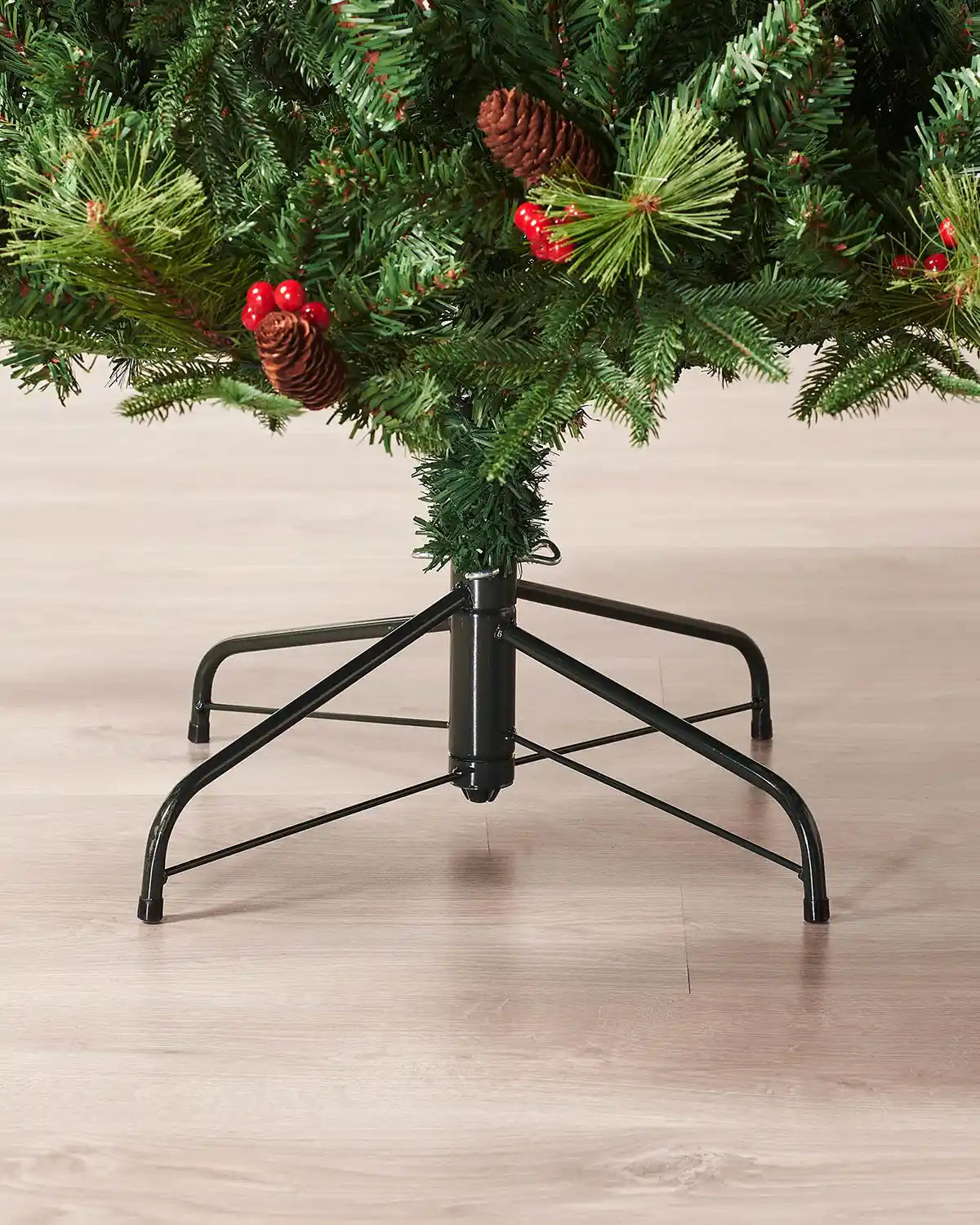 Close up of Black tree stand and base of tree on a Decorated Mixed Tip Berries & Pinecones Christmas Tree, 6 ft