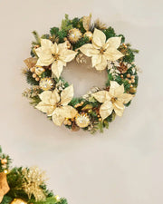 Decorated Wreath with cream flowers, gold baubles, pinecones and glitter leaves on a cream background