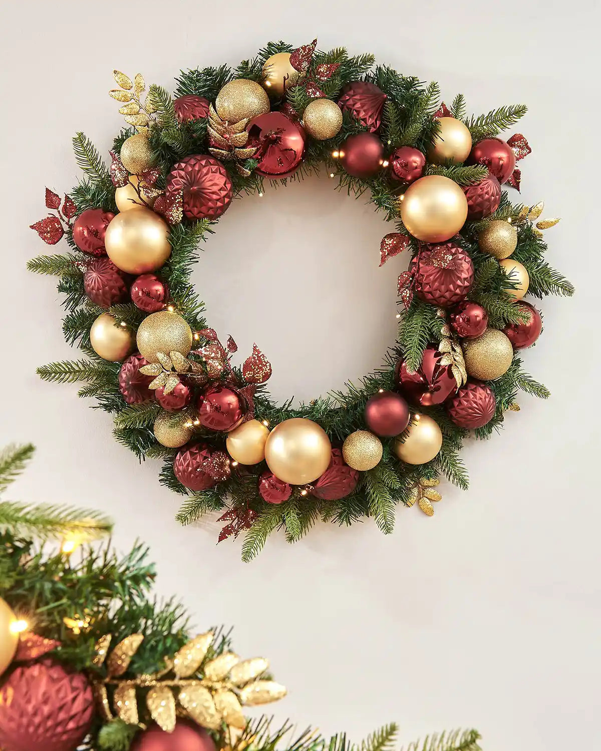 Decorated gold and burgundy wreath on a grey wall