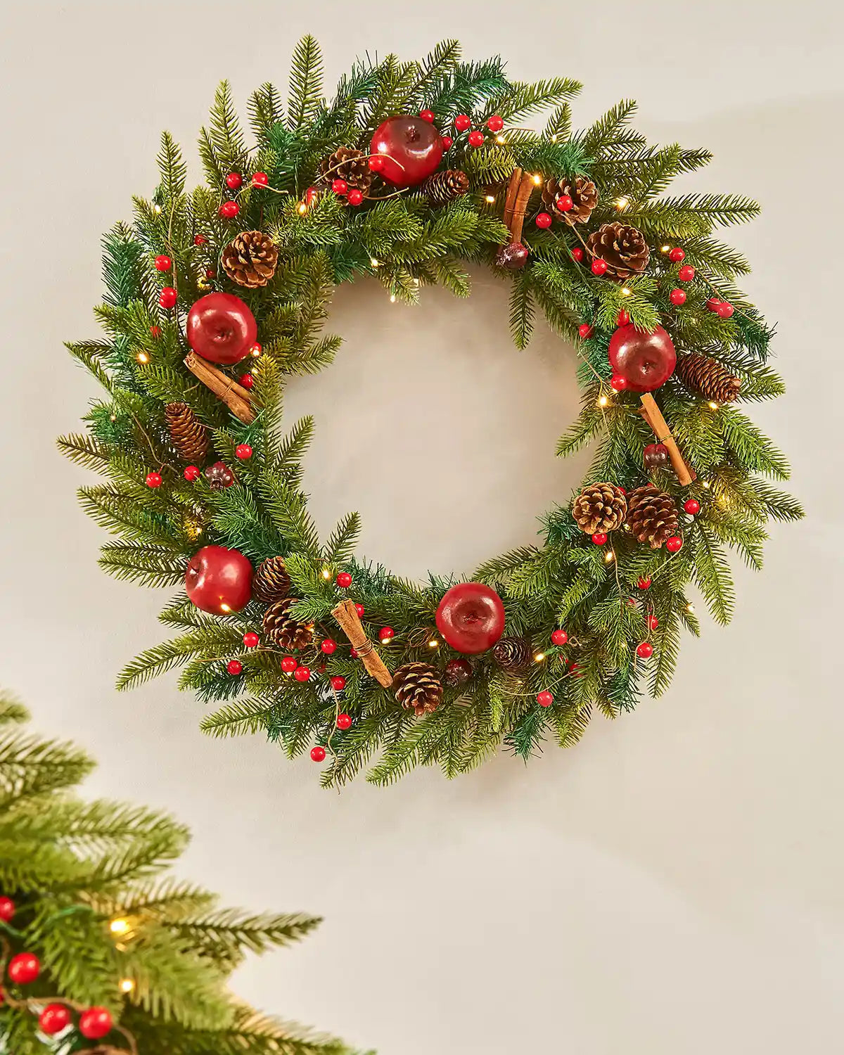 Decorated wreath with Apples and Cinnamon sticks on a cream wall