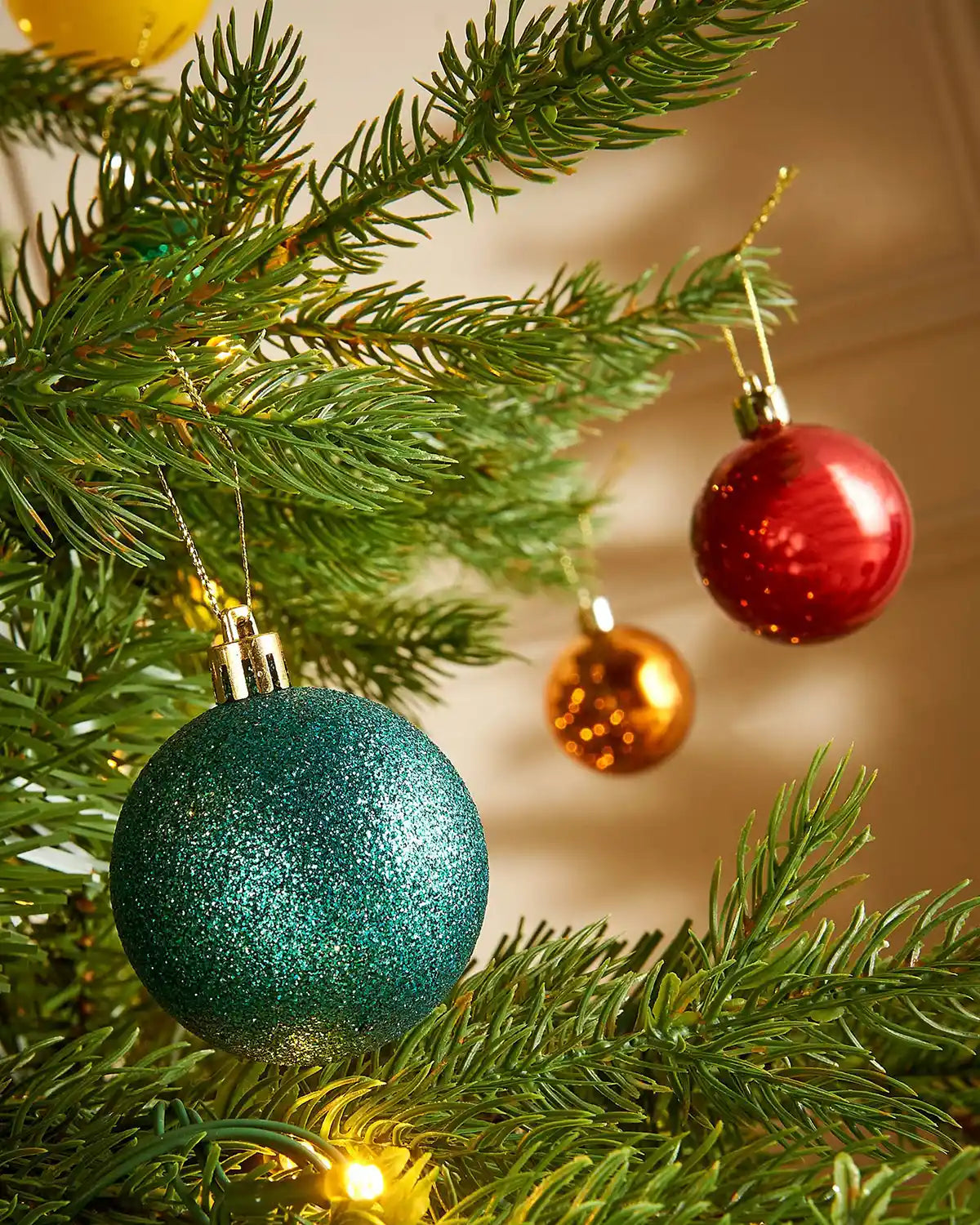 Decorative Christmas baubles close up on a tree branch with a warm background