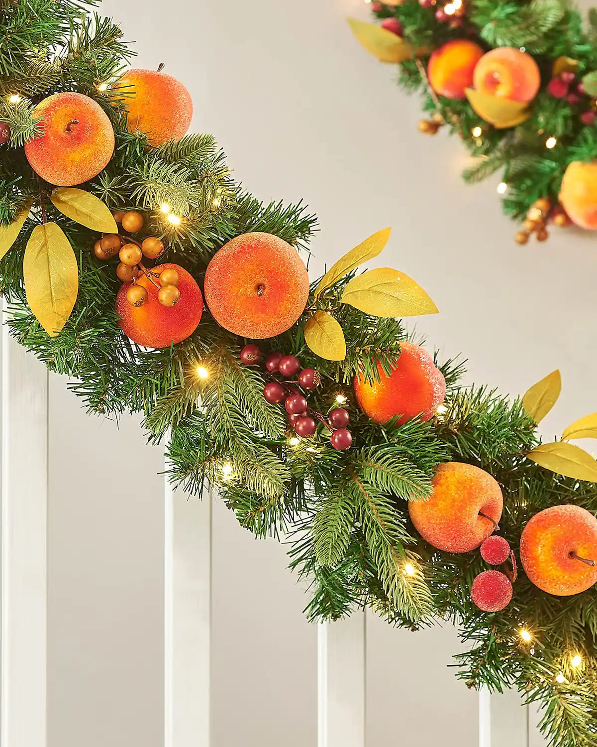 Decorative Christmas garland oranges and peaches and lights on a neutral background