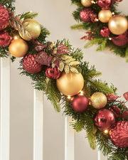 Decorative Christmas garland with burgundy and gold ornaments on a neutral background