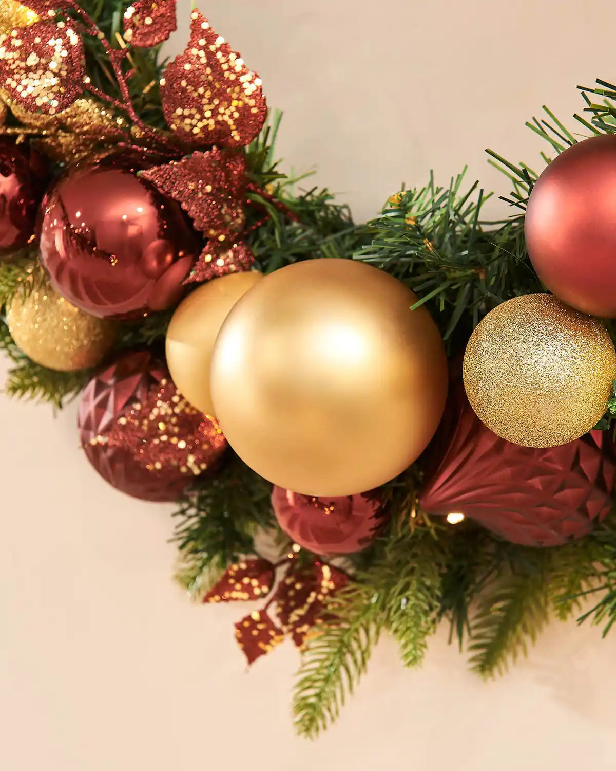 Decorative Christmas garland with red and gold ornaments on a beige background