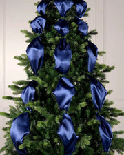 Decorative Christmas tree with blue ribbons against a white wall