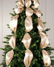 Decorative Christmas tree with latte ribbons against a white wall.