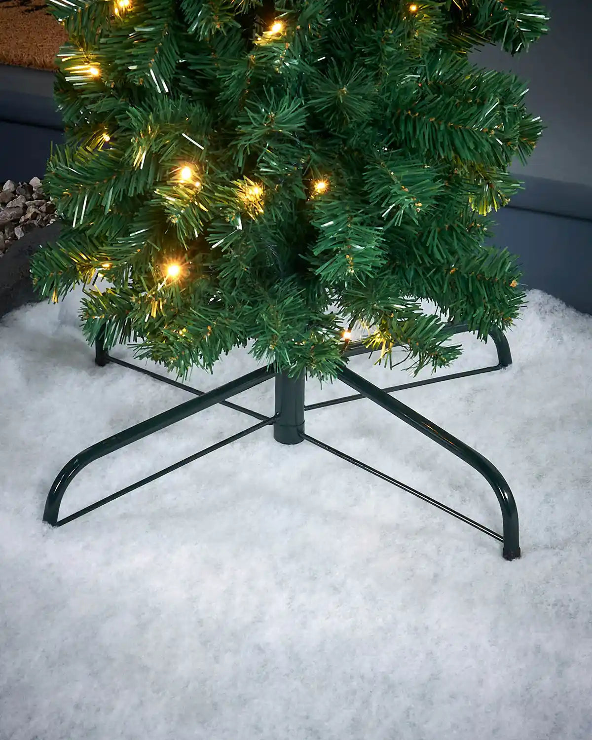 Decorative Christmas tree with lights on a stand in a snowy setting