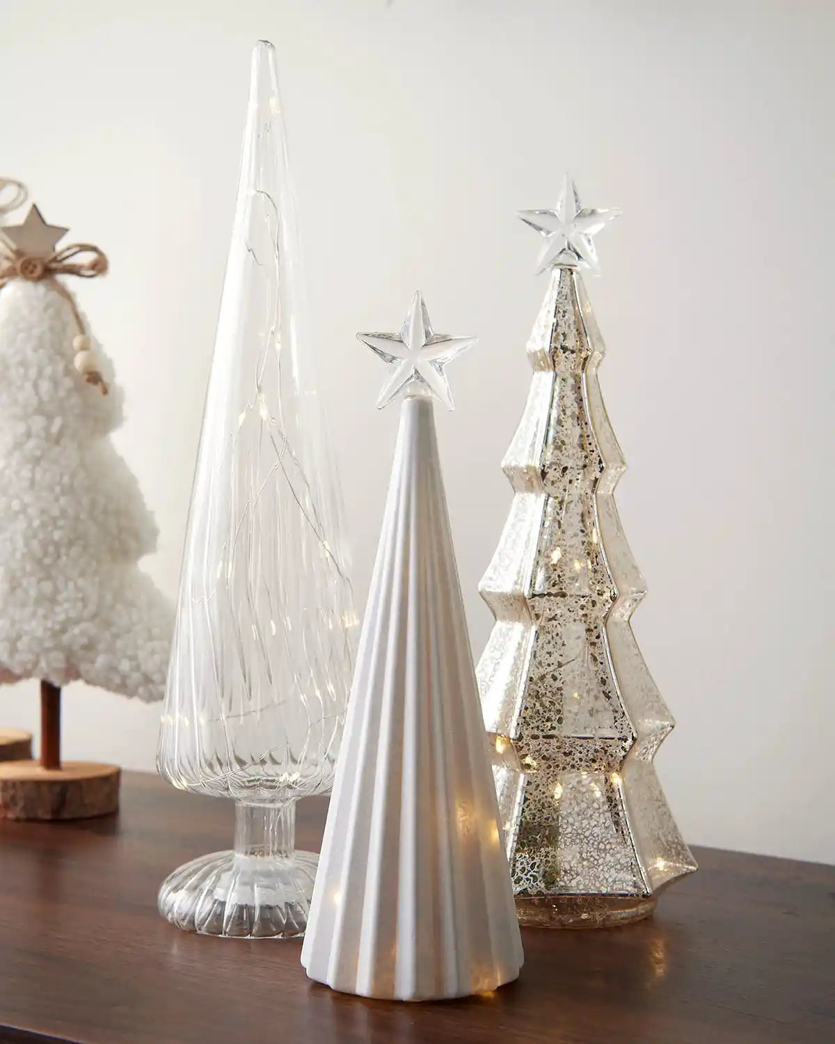 Decorative Christmas trees with star toppers on a wooden surface.