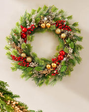 Decorative Christmas wreath with greenery, red berries, and gold ornaments on a cream background