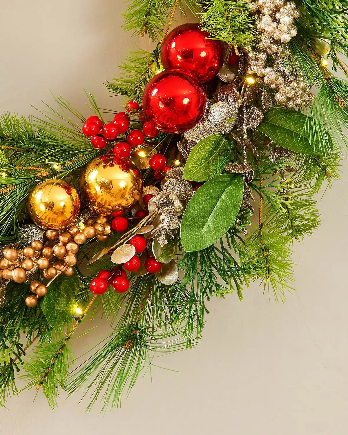 Decorative Christmas wreath with red and gold baubles on a cream background