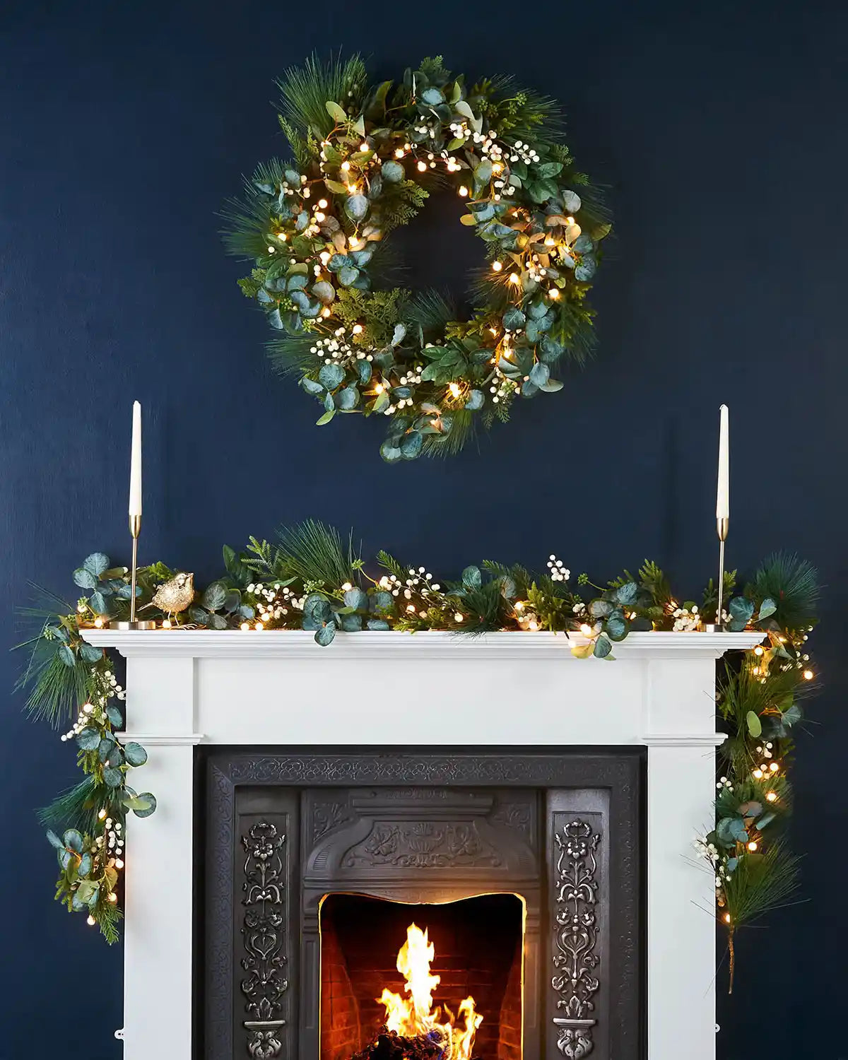 Decorative  Eucalyptus
 wreath and garland on a fireplace with a dark blue wall background