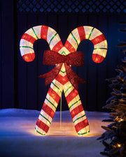 Decorative LED White and red candy cane with a bow on a dark background and snowy grass