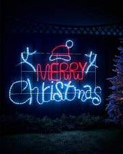 Decorative LED sign with 'Merry Christmas' text in ice white and red lights against a night time scene on a garden fence