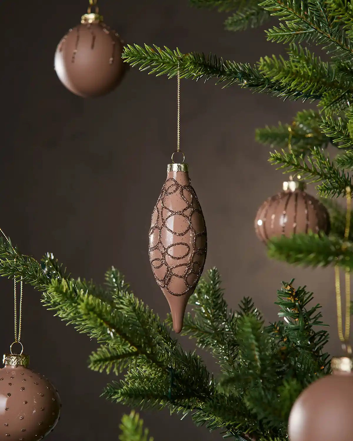 Decorative Latte Christmas baubles with intricate pattern hanging on a tree branch.