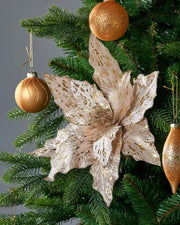 Decorative Poinsettia flower with gold and white petals on a Green Christmas tree and Gold baubles