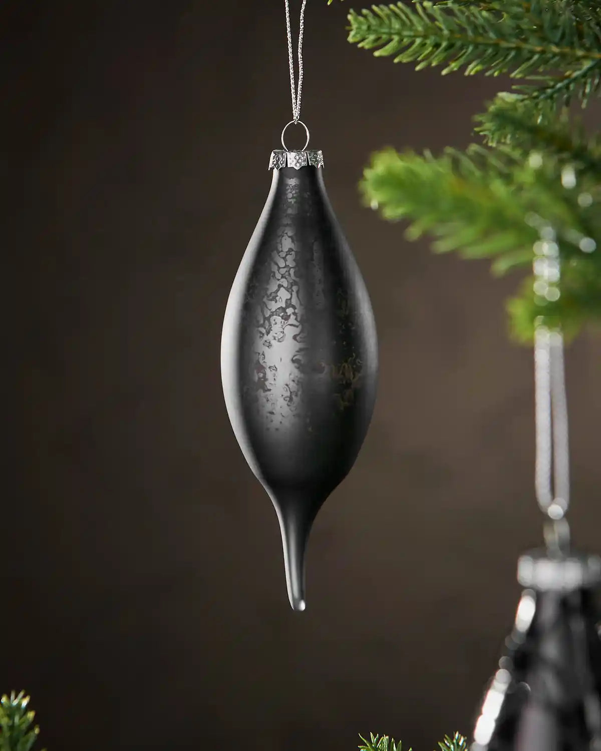 Decorative black bauble hanging on a tree branch with a dark background