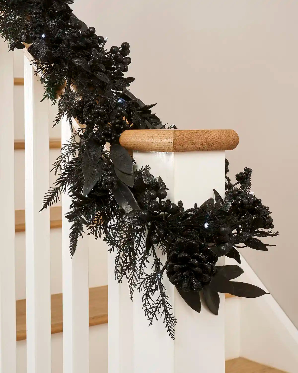 Decorative black garland on a staircase railing with wooden handrail.