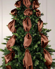 Decorative espresso ribbons on a Christmas tree against a white wall.