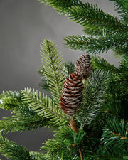 Decorative frosted branch with frosted pine cones on a Christmas tree against a grey background