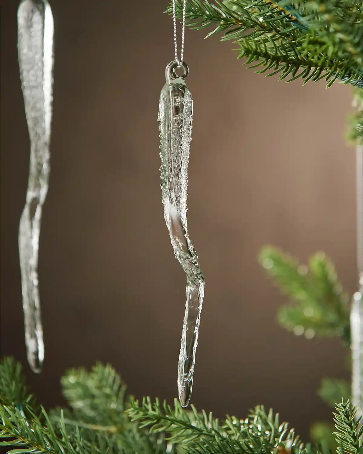 Decorative frosted icicle ornaments hanging on a Christmas tree.