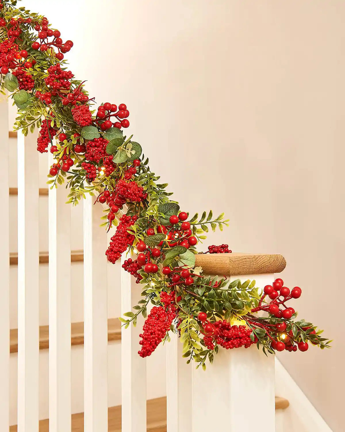 Decorative garland with red berries and green leaves on a staircase banister
