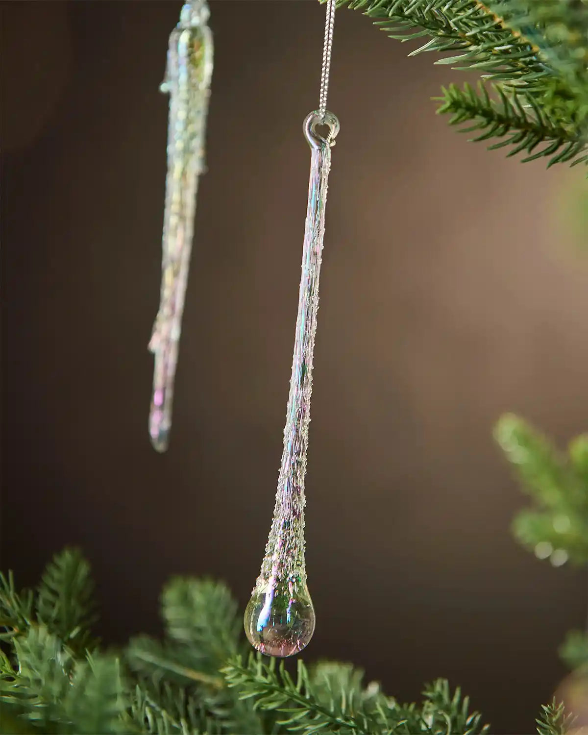 Decorative glass teardrop ornaments hanging on a Christmas tree.