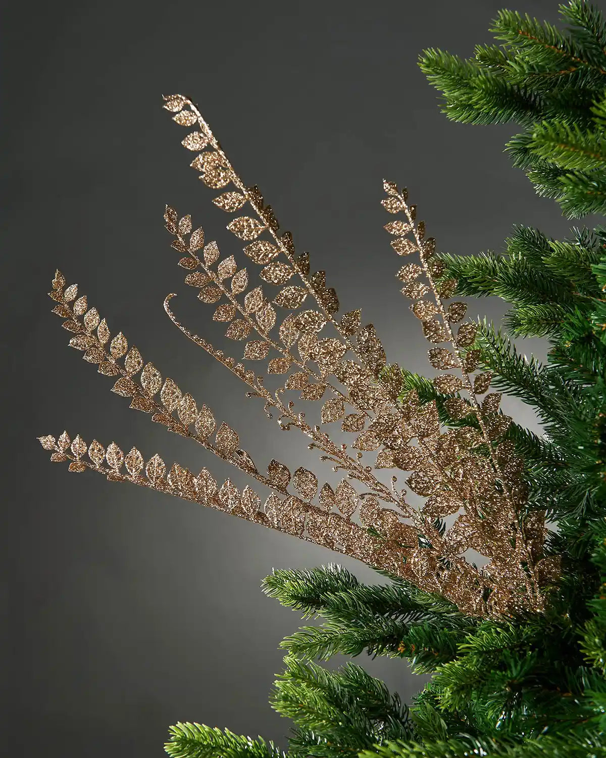 Decorative glitter gold leaf branch on a Christmas tree against a dark background