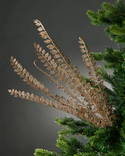 Decorative glitter gold leaf branch on a Christmas tree against a dark background