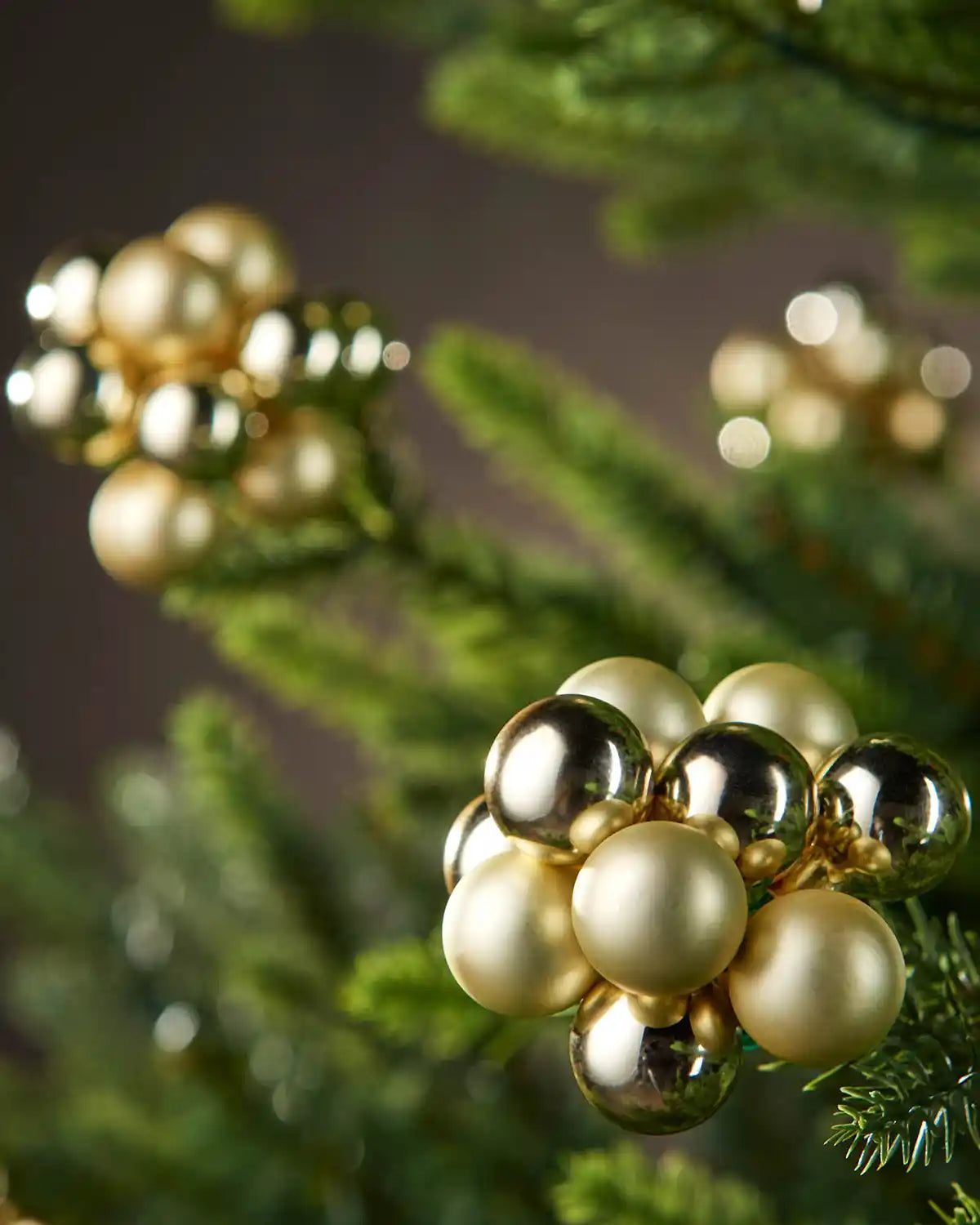 Decorative gold and pearl ornament on a Christmas tree branch.