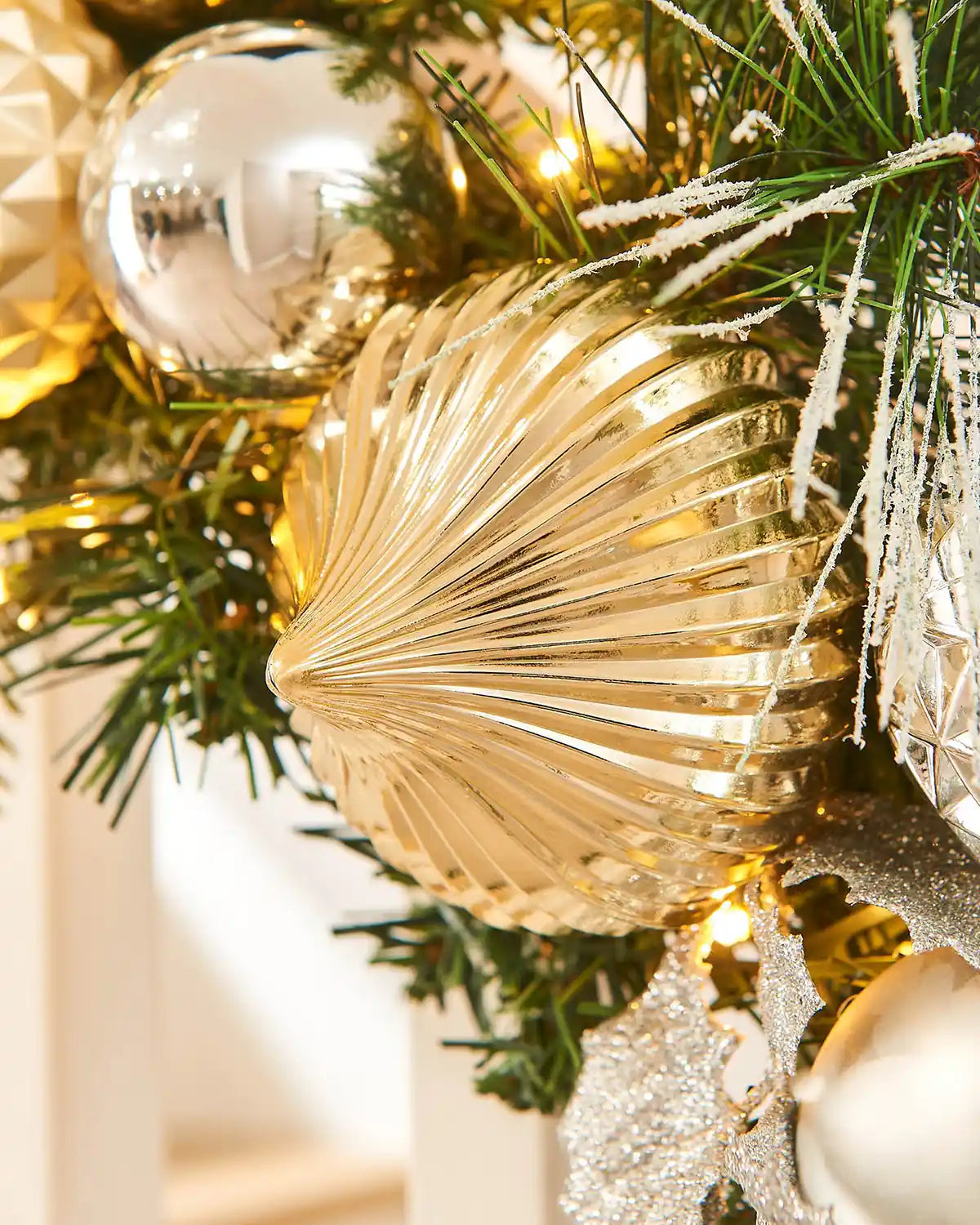 Decorative gold baubles on a Christmas garland with green branches and other ornaments.