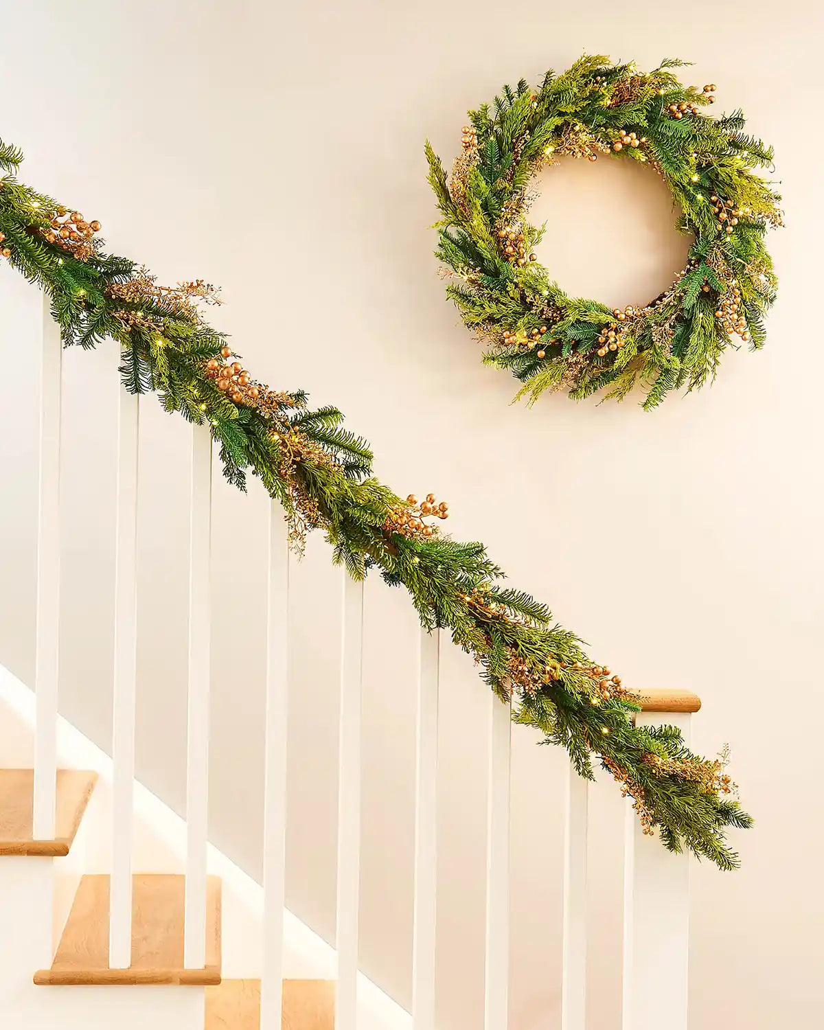Decorative gold berries green wreath with matching garland on a staircase with a Cream background