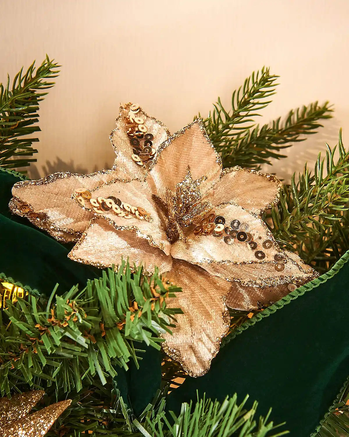 Decorative gold poinsettia flower on a green Christmas tree branch with Green velvet ribbon